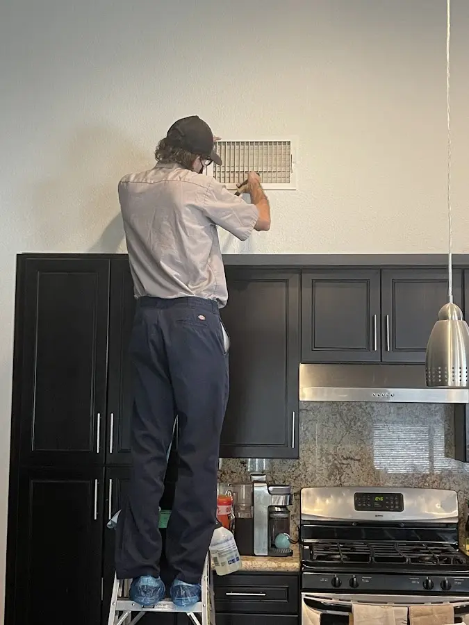 Technician inspecting an air vent during HVAC service in Clayton